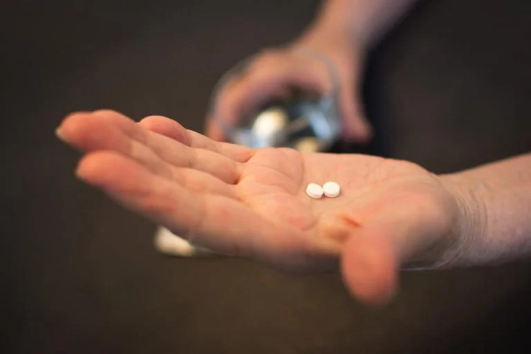 Hand holding two white pills
