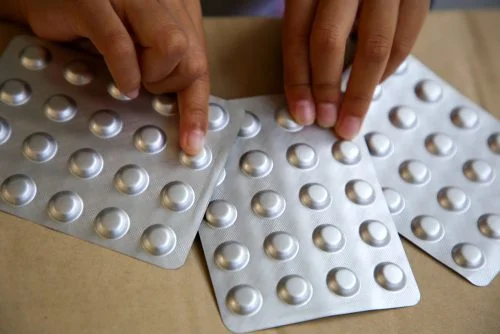 Hands holding blister packs of pills